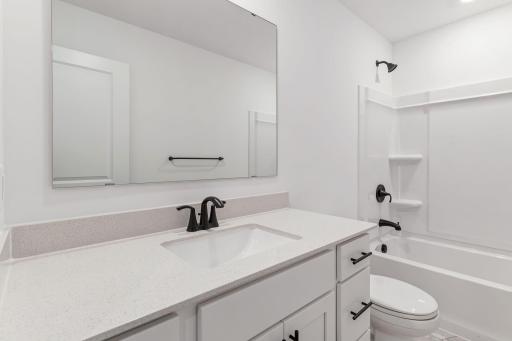 Situated near the secondary bedrooms, this full-sized bathroom comes well-equipped with a quartz-topped vanity and a combination shower and tub to maximize the interior space.