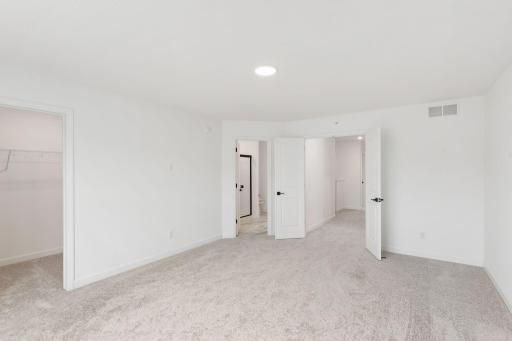 The primary bedroom embraces natural light streaming in from the large windows