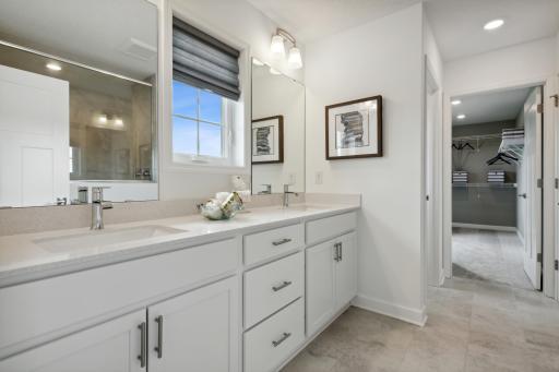(Photo of a decorated model, actual homes finishes will vary) An extension of the primary bedroom, this spacious bath includes a double vanity and a serenity shower.