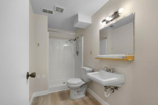 Functional lower-level bathroom with walk-in shower and updated flooring.