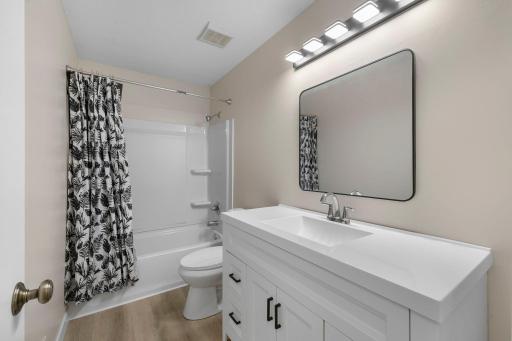 Freshly updated bathroom featuring a modern vanity, sleek lighting, and a full tub with showerâdesigned for comfort and style.