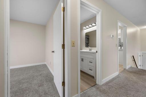 Upper-level hallway with plush carpeting and easy access to bedrooms and a beautifully updated bathroom featuring modern vanity and lighting.