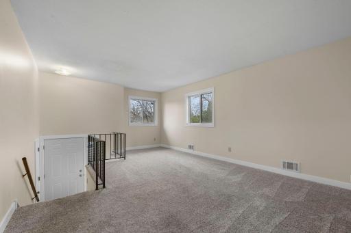Spacious and light-filled living area with fresh neutral tones, plush carpeting, and large windows that bring in plenty of natural light