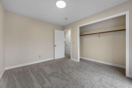 Comfortable bedroom with soft neutral tones, plush carpeting, and a spacious closetâoffering a clean, move-in-ready space with plenty of storage