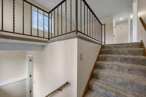 Well-maintained split-level entry with plush carpeting, updated railing, and bright natural light creating a warm and welcoming first impression.