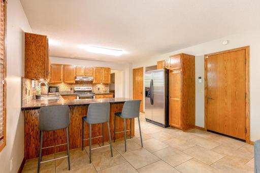 The spacious eat-in kitchen features abundant cabinetry, stainless steel appliances, a stylish tile backsplash, and a large breakfast bar with seating.