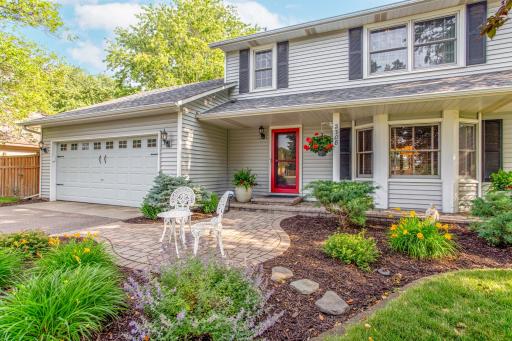The charming front entry welcomes guests with lush perennial gardens, a winding paver walkway, and a covered front porch.