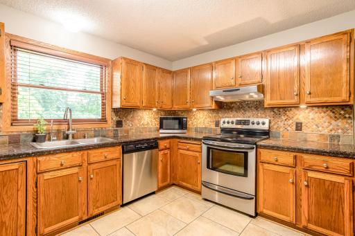 A tile backsplash, stainless steel appliances, and abundant cabinet storage create a warm and inviting kitchen.