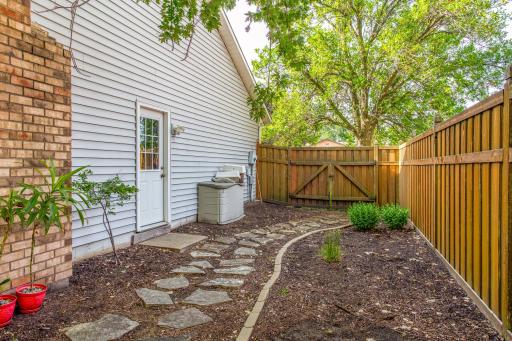 The gated side entrance and stone walkway provide both convenience and secure access to the fully fenced backyard.