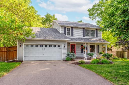 Classic two-story design with an inviting front porch, oversized driveway, and beautifully landscaped grounds.