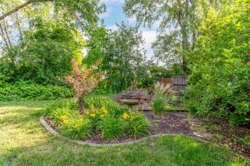 Thoughtfully landscaped perennial gardens and mature plantings add color, charm, and tranquility to this firepit area.