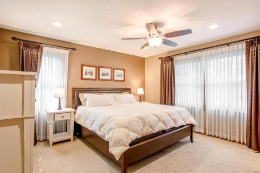 The spacious primary suite offers a peaceful retreat with large windows, recessed lighting, and a ceiling fan.