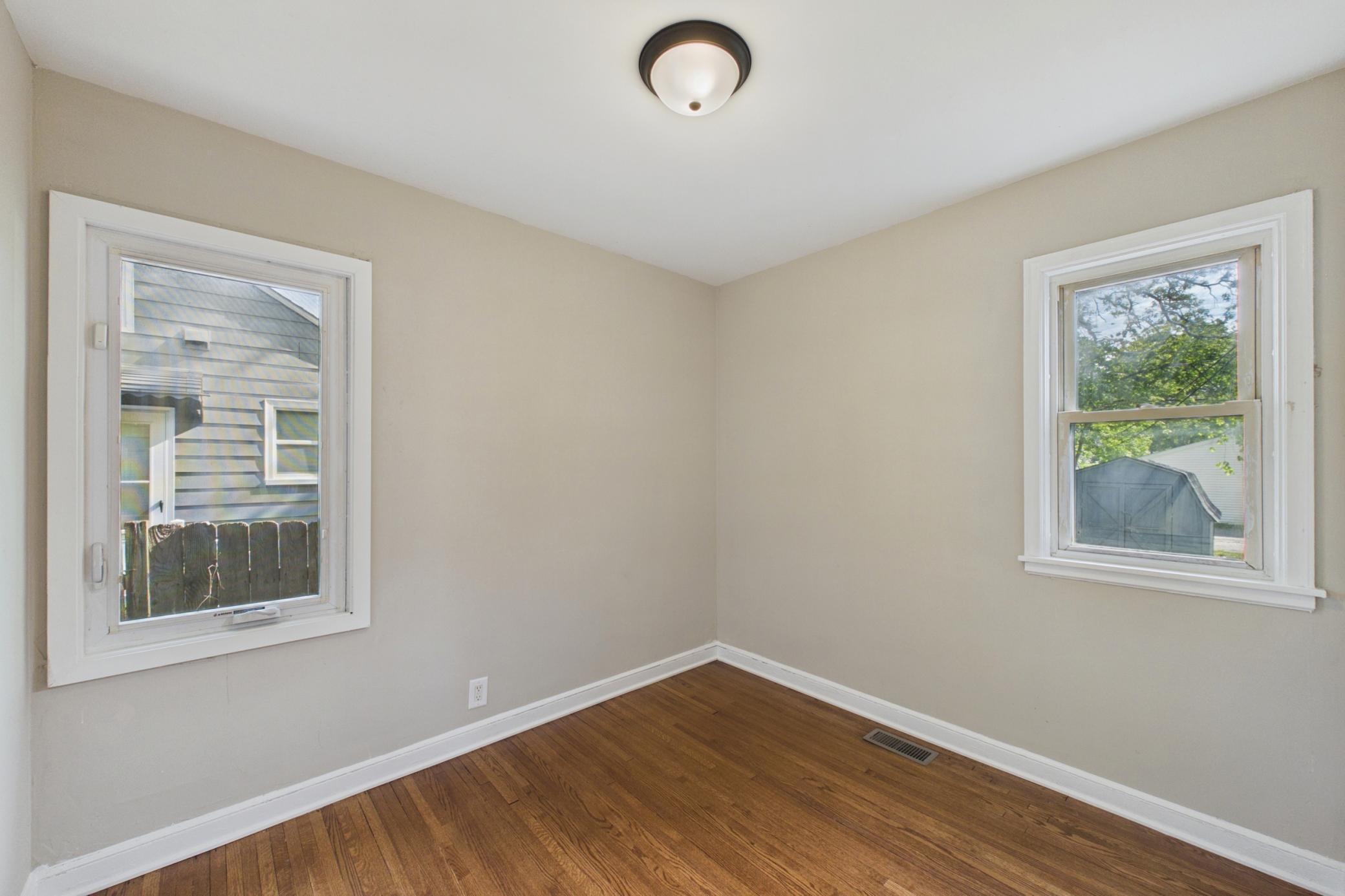 Secondary bedroom with hardwood floors and backyard views.
