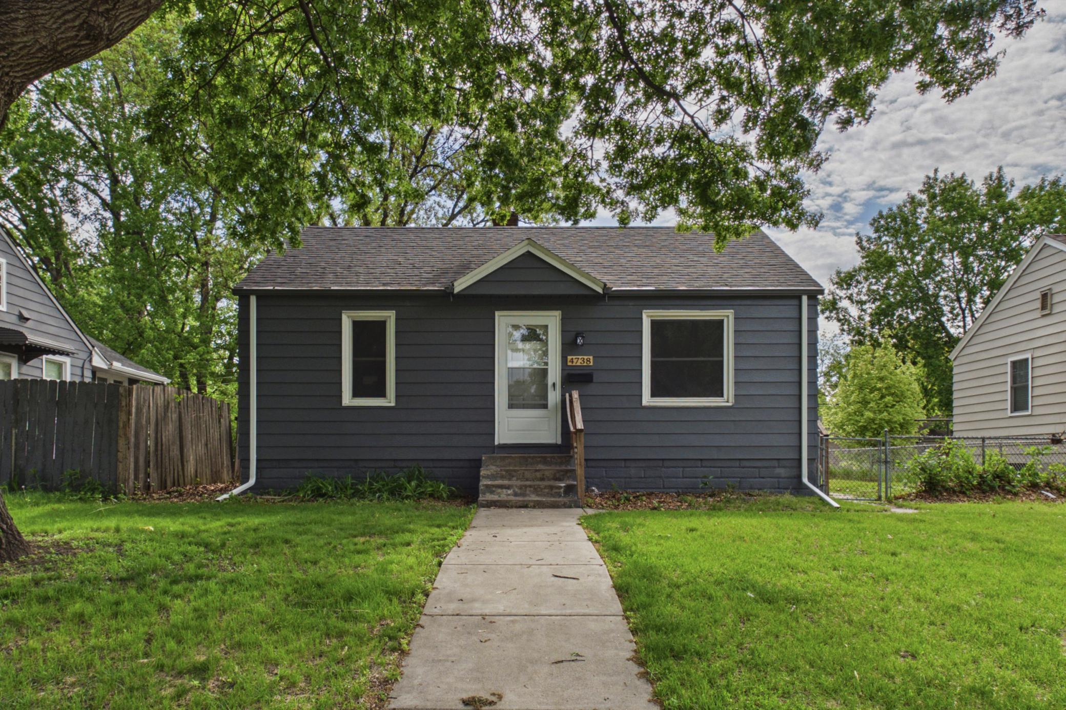 Front exterior with mature trees, fenced yard, and updated exterior paint.