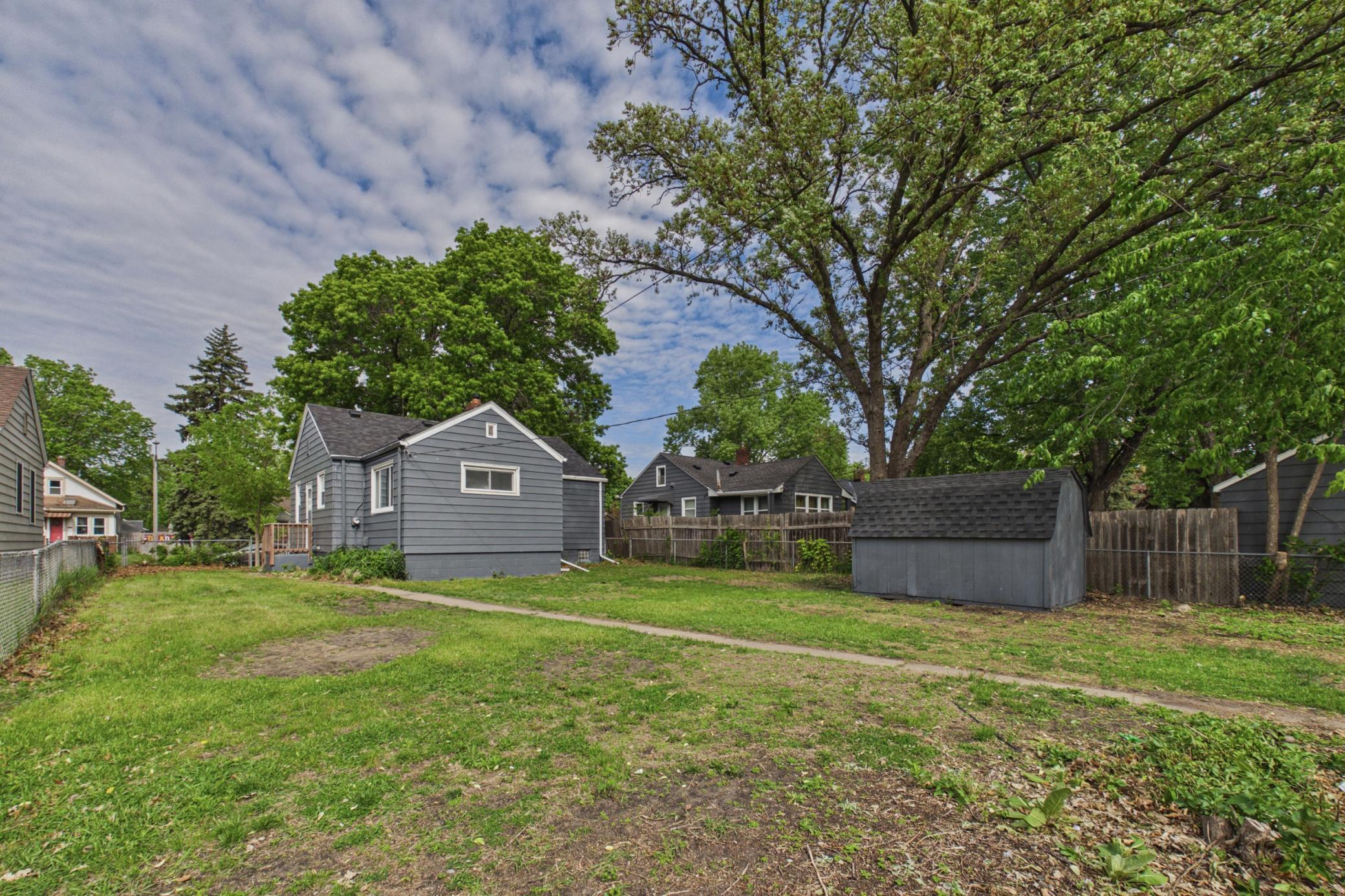 Large backyard with mature trees and storage shed.