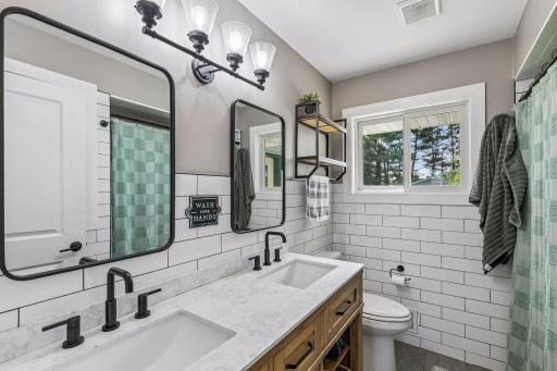 Main level full bathroom w/ double sink & beautiful tile work throughout.