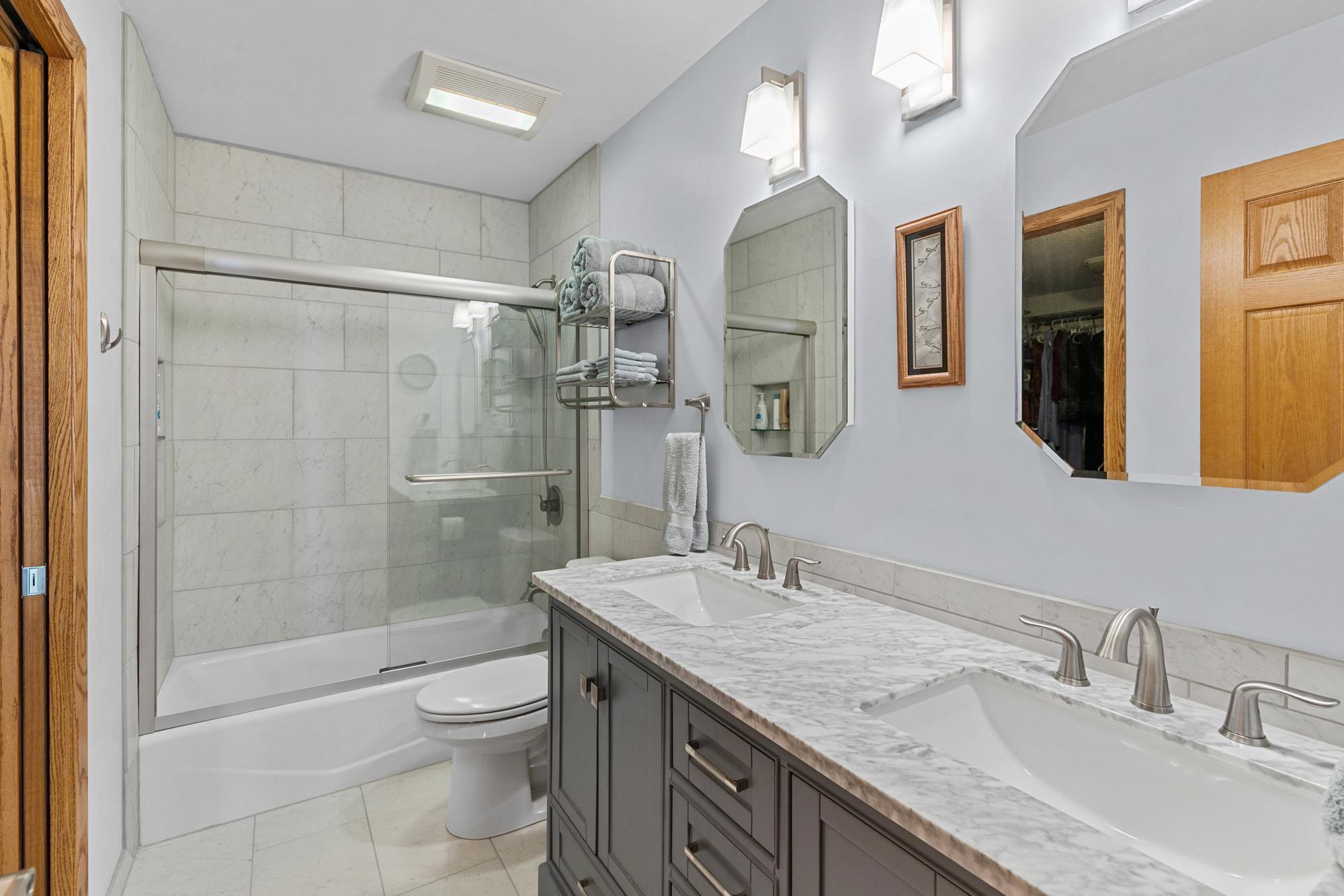 Main level full bath. Reworked / remodeled with extraordinary fixtures and features. Dual sink vanity, solid surface countertop, custom ceramic tile flooring and shower surround.