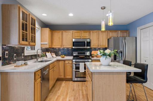 Center island with breakfast bar, stainless appliances, solid surface countertops and closet pantry.