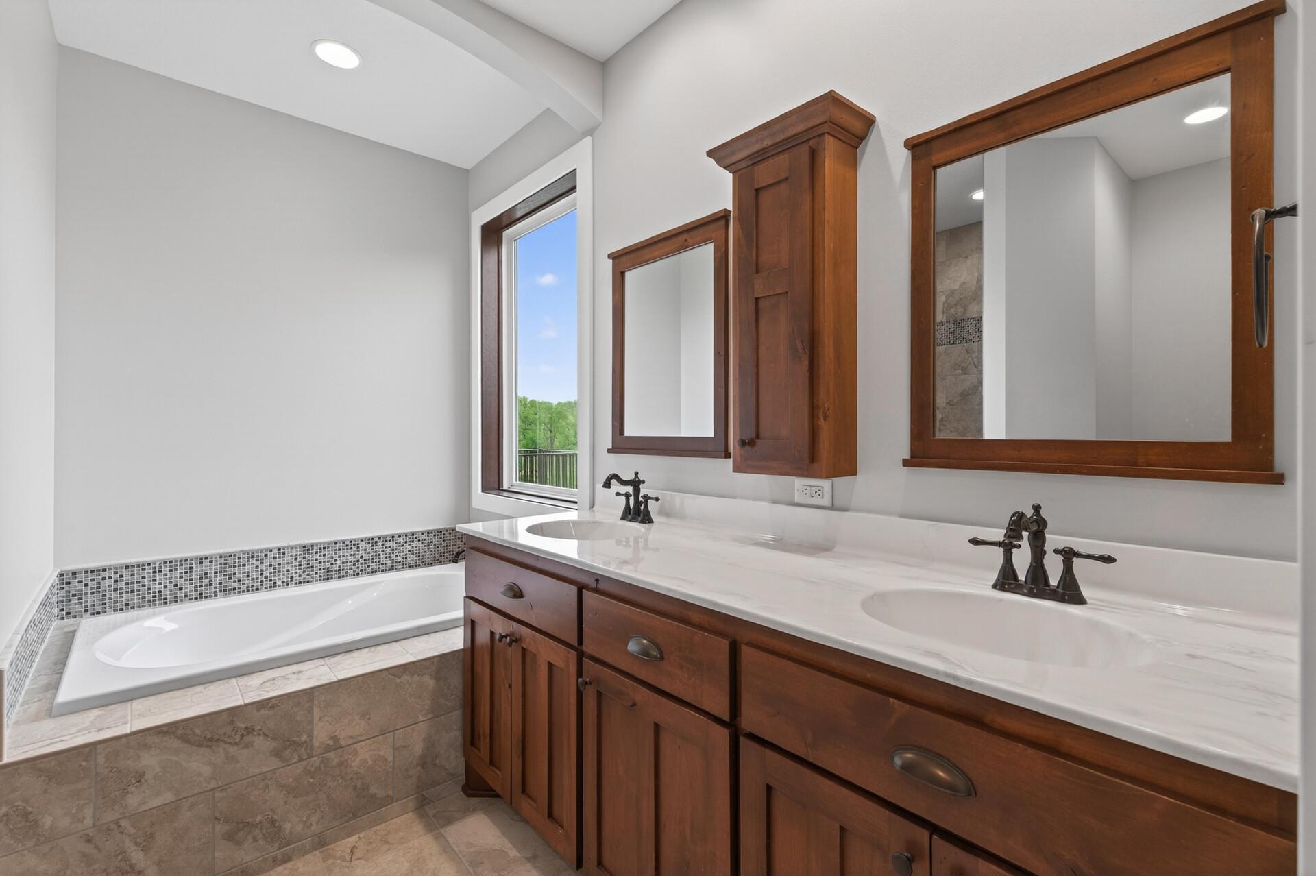 Custom cabinetry, double sinks, jetted tub, and walk around tiled shower.