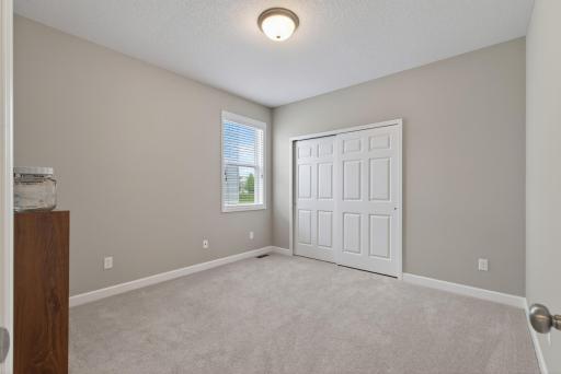 Second main level bedroom with neutral paint and plush carpeting.