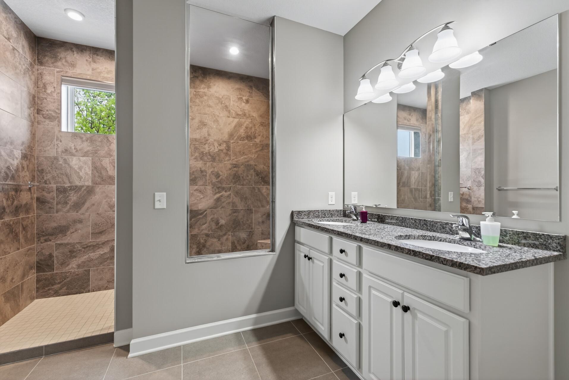 Another stunning space! This primary ensuite offers a dual sink vanity and generous walk-in shower.