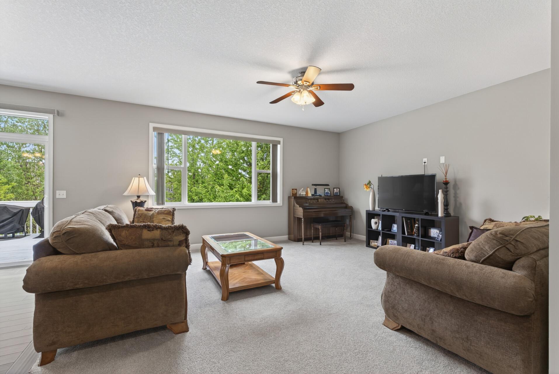 The living room features cozy carpeting and a ceiling fan for added comfort year round.