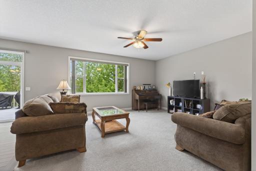 The living room features cozy carpeting and a ceiling fan for added comfort year round.