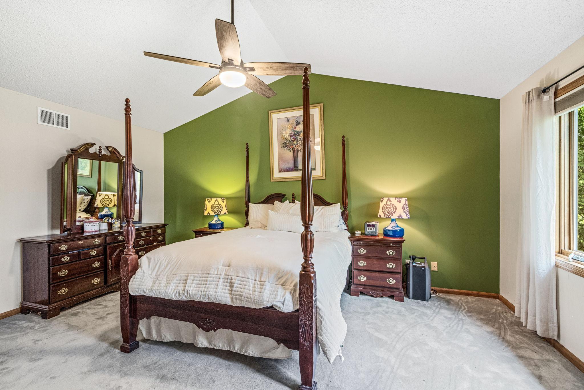 Large primary bedroom with ceiling fan, and large windows.