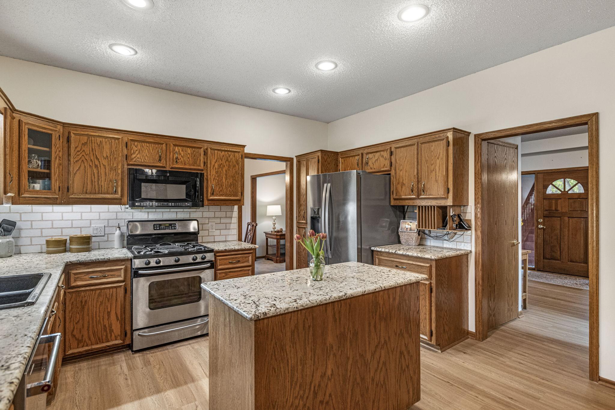 Kitchen with oak cabinets, granite counters, island, and stainless appliances