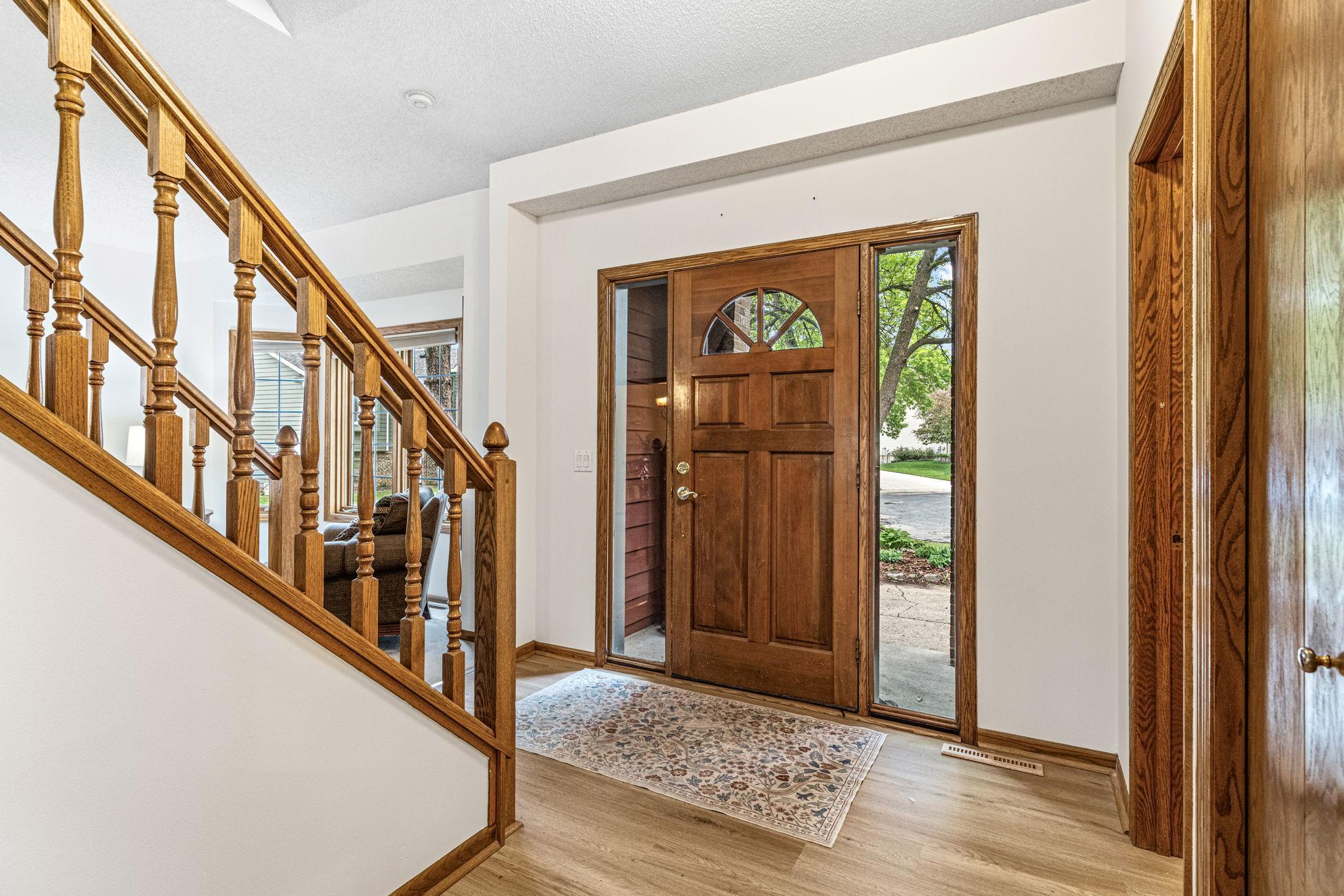 Welcoming foyer with beautiful flooring, oak staircase, and a solid wood entry door.