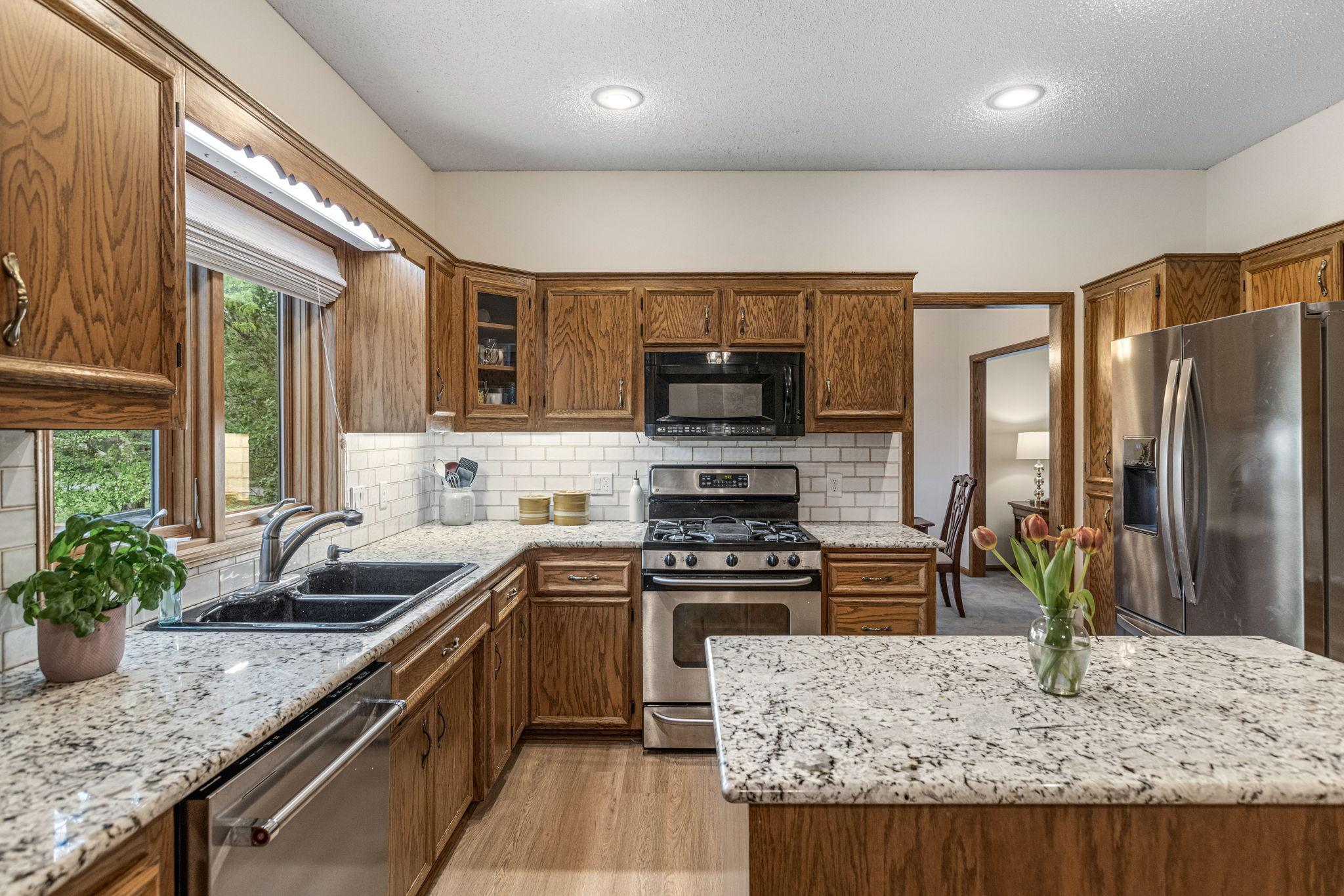 Kitchen detail with gas range, granite counters, and sink window