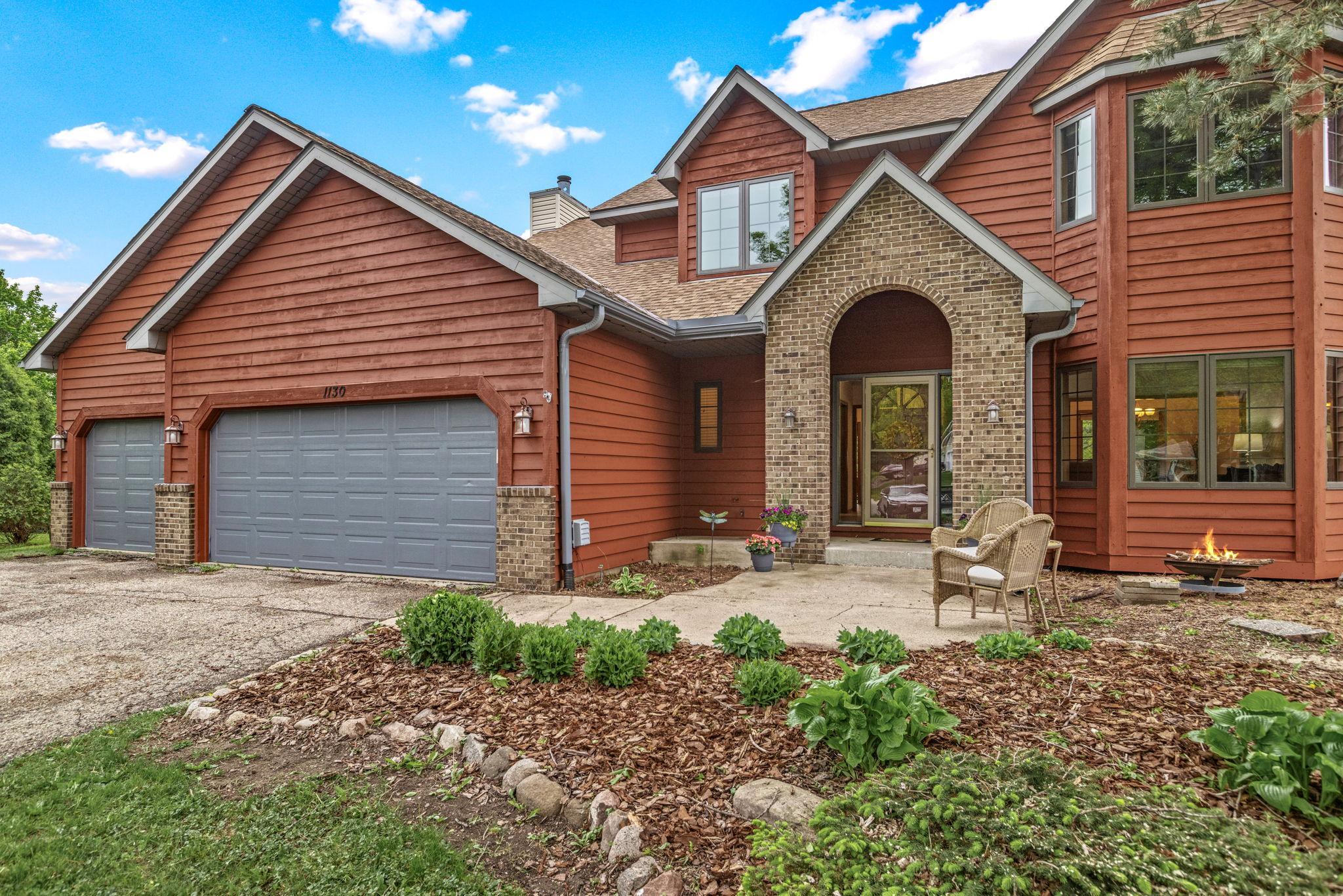 Front exterior featuring wood siding, arched entryway, and manicured landscaping with mulched garden beds.