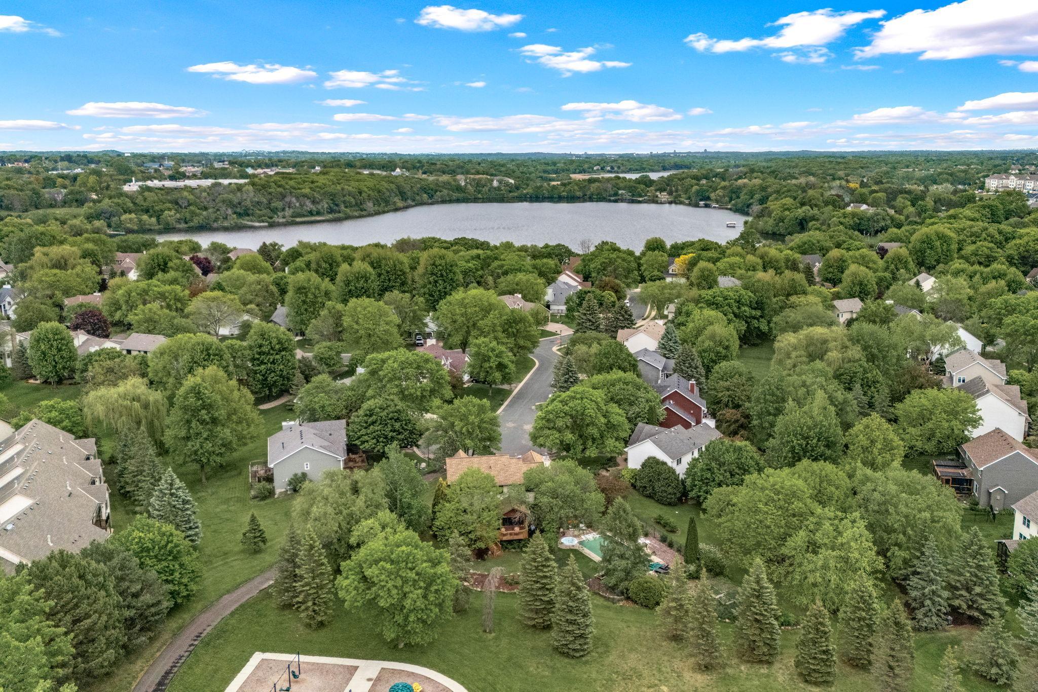 View of the neighborhood with mature trees and park area behind home.