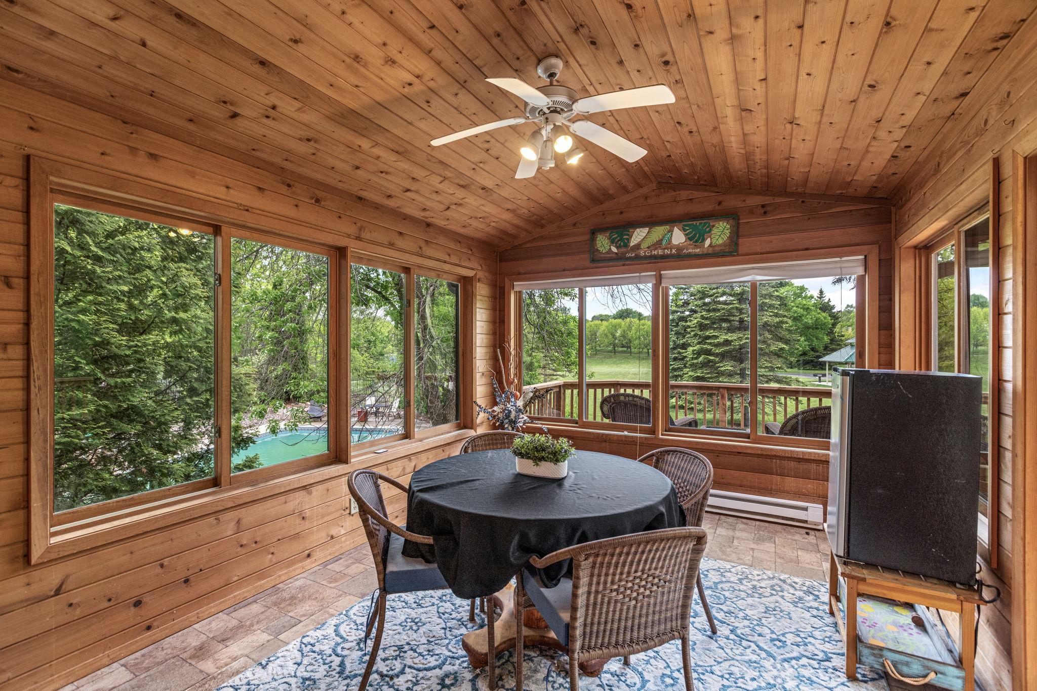 Three season porch with cedar walls, vaulted ceiling, and views of the pool, backyard, and neighborhood park.