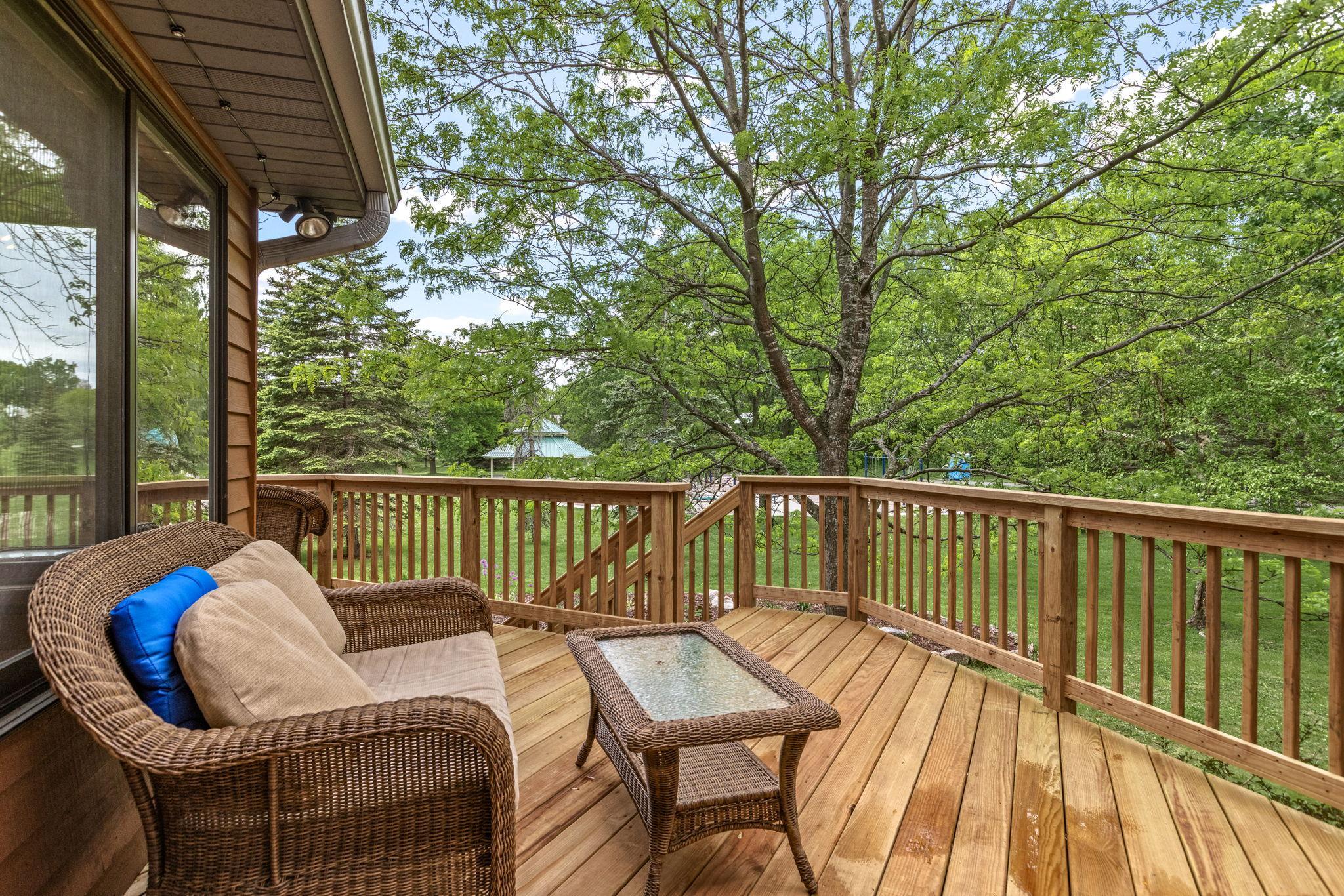 Deck wraps around the three season porch and looks over the pool area, neighborhood park, and open play space. No direct neighbors behind the home.