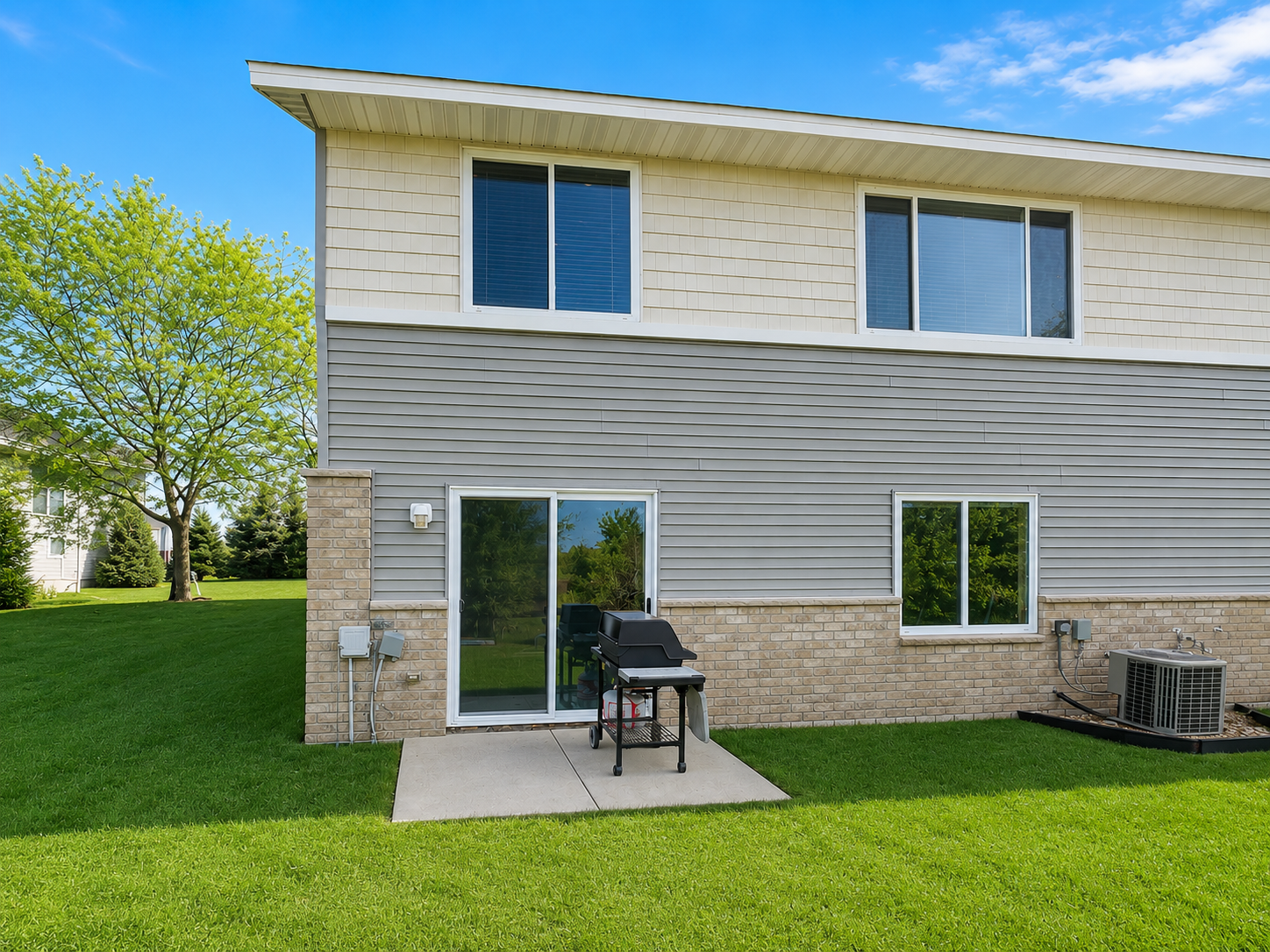 Back view of the home showing the lovely walk-out with a concrete slab perfect for a grill and/or chairs for seating.