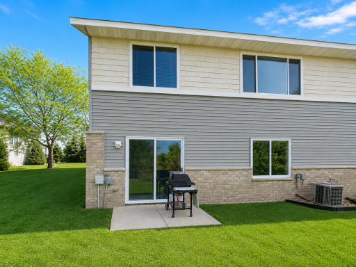 Back view of the home showing the lovely walk-out with a concrete slab perfect for a grill and/or chairs for seating.