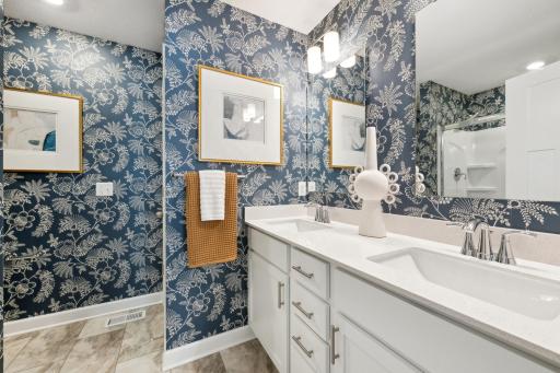 (Photo of decorated model, actual home's finishes will vary) The owner's bathroom offers a double-vanity with quartz countertops, a linen closet, and shower.