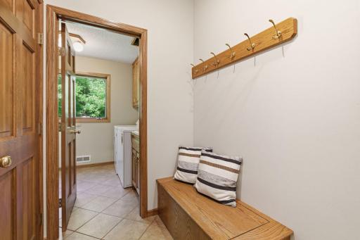 Large mudroom boasts walk-in closet and built-in boot bench and coat hooks.