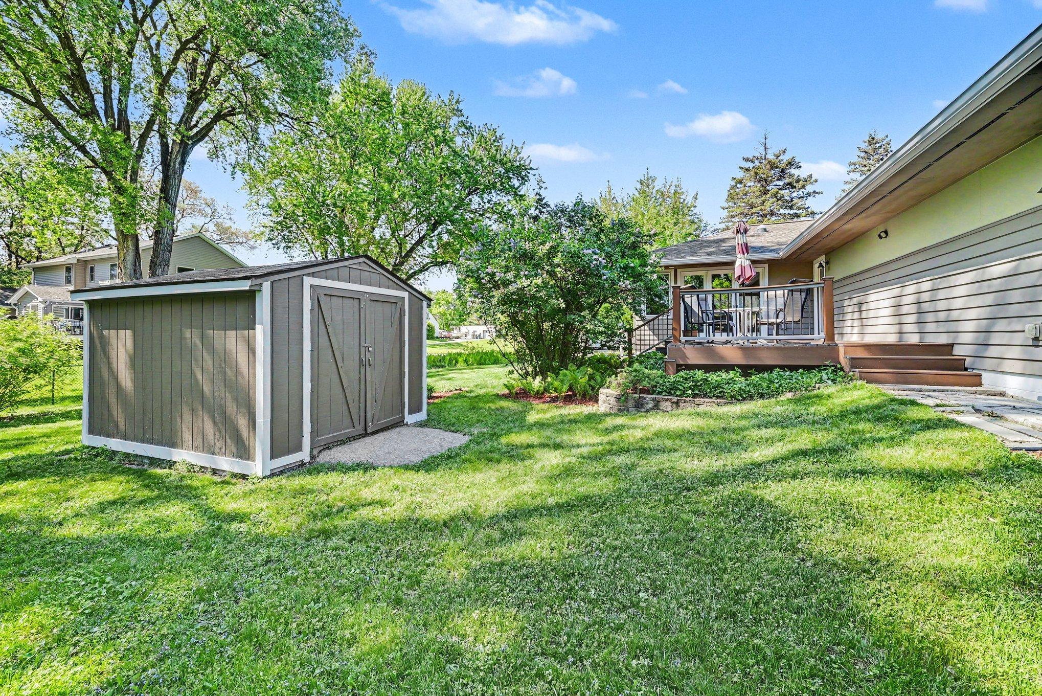 Backyard perspective behind garage featuring shed and west deck