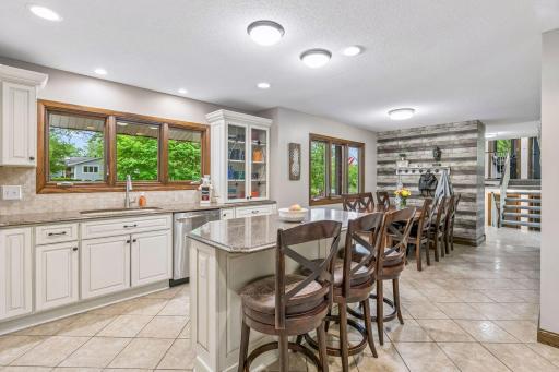 This is a bright room with a bank of windows looking out to the front yard and both ceiling light fixtures and recessed lighting.