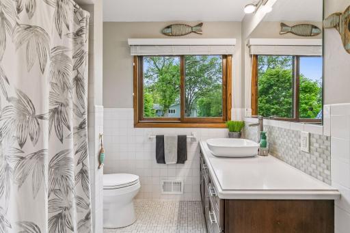 The full bathroom on the upper level has ceramic wall and floor tile, an updated vanity with long counter and vessel sink.