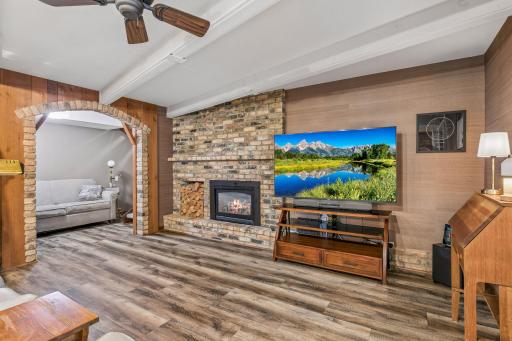 There is a wood burning fireplace with brick surround and ceiling beams for architectural interest. To the left you can see a quiet seating niche off to the side.
