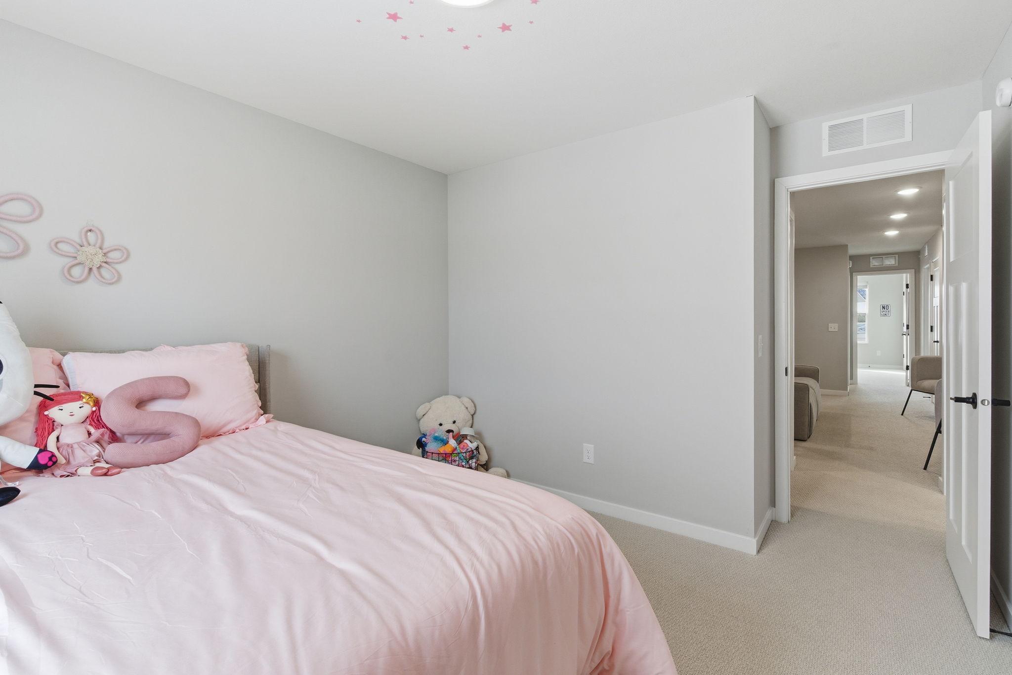 The second bedroom, conveniently located near the primary suite, offers plush carpet underfoot and generous closet space, providing flexibility for a guest room, nursery, or private office.