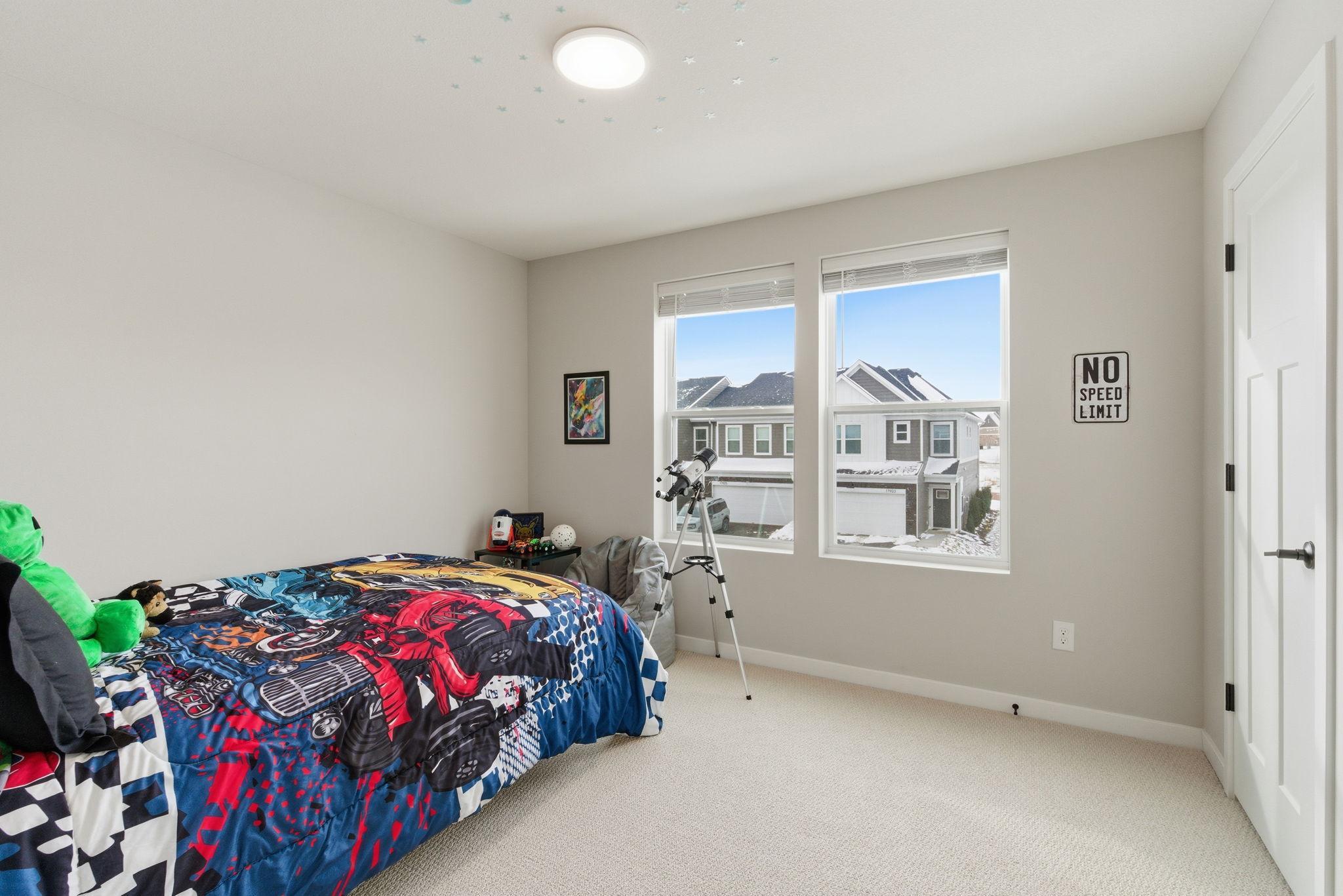 This bright and inviting upper-level bedroom offers comfort, flexibility, and thoughtful design. Plush carpeting, soft neutral tones, and oversized windows create a light-filled retreat ideal for rest or productivity.