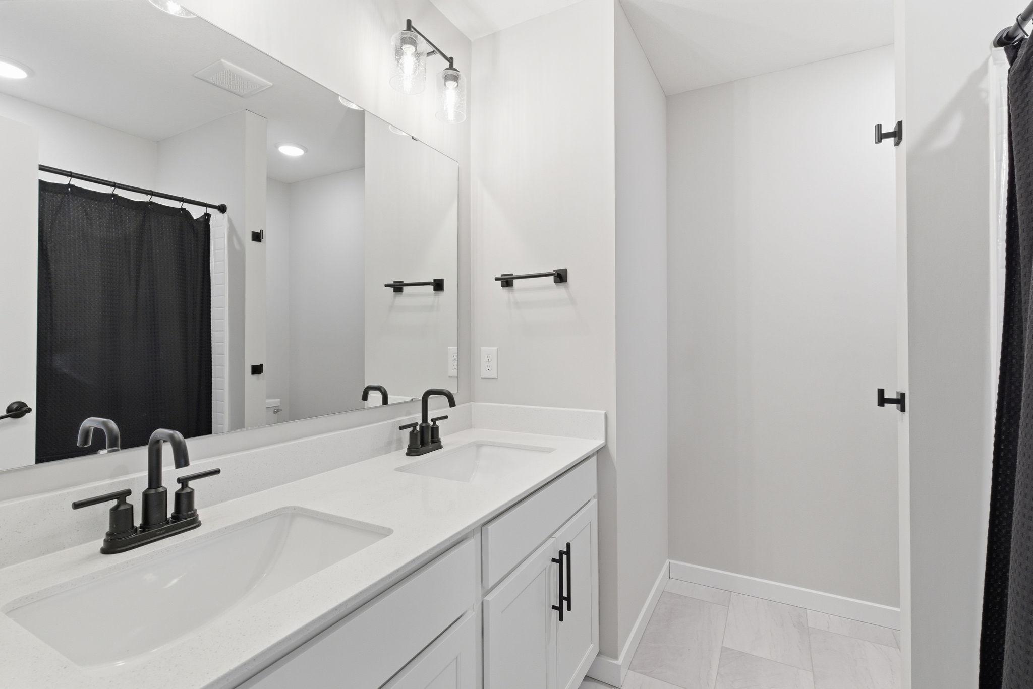 The upper-level full bath features an undermount double vanity, elegant tile flooring, and a beautifully tiled tub surround—designed to elevate everyday routines with a spa-inspired finishes.