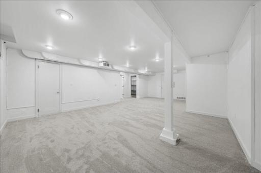Additional view of lower level family room door straight ahead leads to Lower Level 3/4 Bathroom And at the far end of the image one door leads to workshop storage room & 2nd door leads to a large laundry room/ storage space