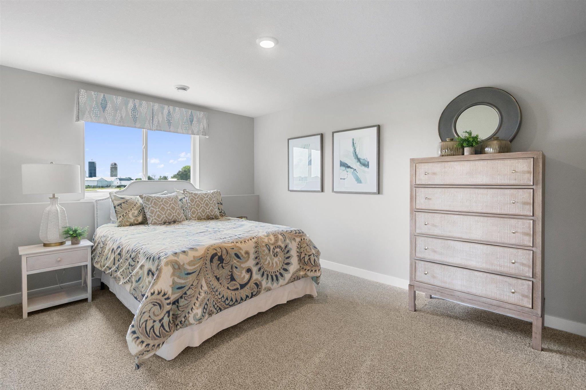 Tucked down in the lower level, and away from the hustle and bustle of the main level living spaces, this bedroom resides adjacent to a full bath and serves as the perfect guest room or your home office! Photo is of actual home.