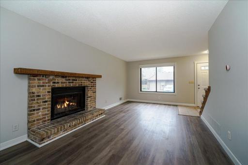 Living room offers a woodburning fireplace w/ brick surround and Lvp flooring.
