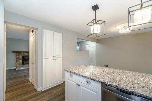 Kitchen features granite countertops, enameled woodwork, stainless steel appliances, LVP flooring and peninsula island w/ stylish pendant lighting.